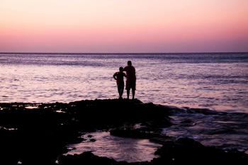 Father and Child Near on Body of Water during Sunset