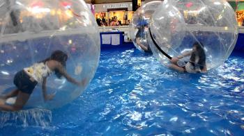 Asian girls inside large plastic balls while floating on water ...