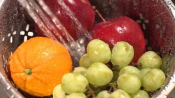 Slow motion close up of fruit being washed by spraying water in a ...