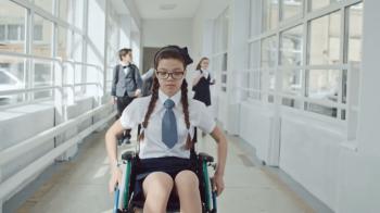 Disabled girl riding wheelchair at school while her friends running ...