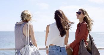 Teenage girls hanging out at beach on summer vacation sitting on ...