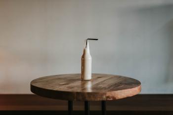 Glass Bottle Filled With Black Straw on Brown Wooden Table