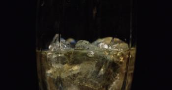 Tilt up from the bar to a glass being filled with alcohol / liquor ...