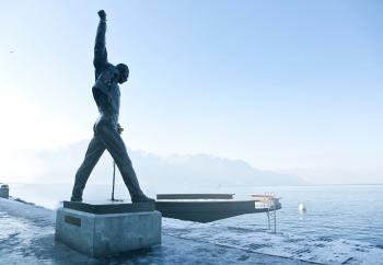 Gray Metal Statue of Man Raising Hand Near Dock