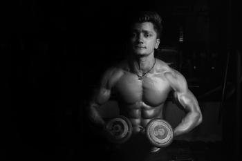 Grayscale Photo of a Man Holding Pair of Dumbbells