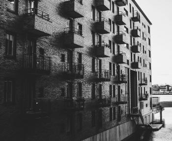 Grayscale Photo of Building Beside Body of Water