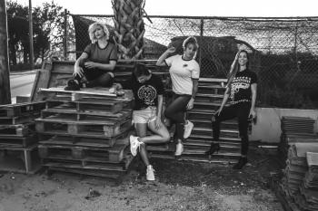 Grayscale Photo of Four Women on Wooden Pallets