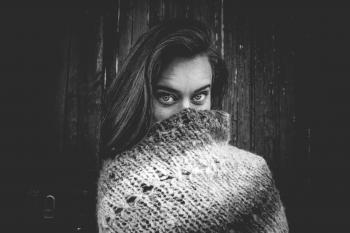 Grayscale Photo of Woman Covering Mouth With Knitted Textile