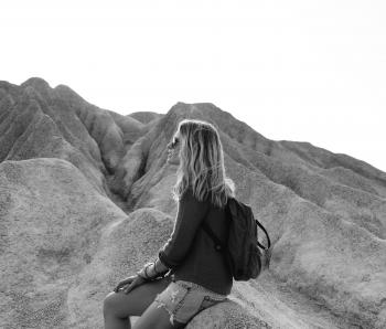 Grayscale Photo of Woman Sitting on Rock