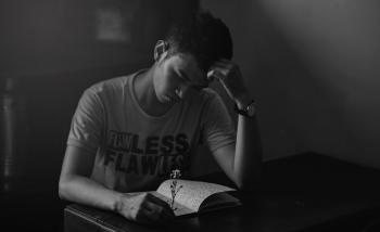 Grayscale Photography of Man in Shirt Reading Notebook