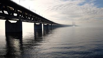 Grey Concrete Bridge on Body of Water Under Blue and White Sky during Daytime