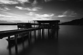Greyscale Photo of Dock Near Mountains