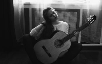 Greyscale Photography of Woman in Crew Neck Long Sleeve Shirt Holding Guitar