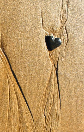 Heart-shaped pebble in the sand
