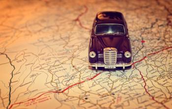 Hit the road - Travel concept with vintage miniature car on road map