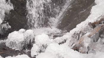 Iciciles bellow waterfall. Snowy and icy stones and boulders with ...