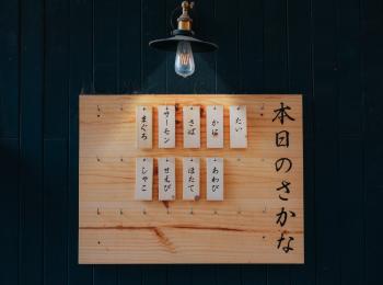 Kanji Printed Tags Hanged on Brown Wooden Board Lighted by Pendant Lamp