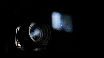 Cinema projector lens and blurred movie image on glass, closeup view ...