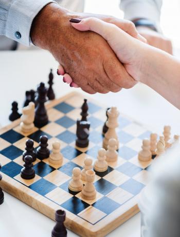Man and Woman Shaking Hands over a Game of Chess