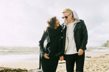 Man and Woman Wearing Jackets Near Seaside Under Cloudy Sky