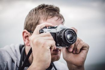 Man Holding Black Silver Bridge Camera Taking Photo during Daytime