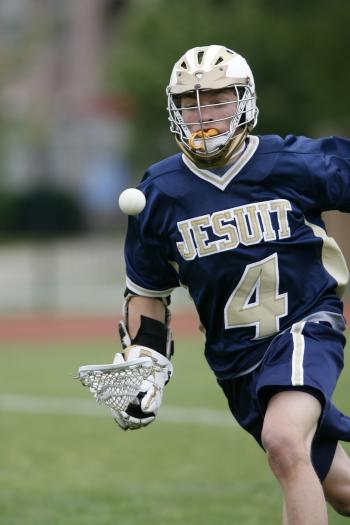 Man Holding Lacrosse Stick Running on Field during Daytime