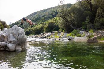 Man in Black Shorts Back Flipping Into River during Daytime