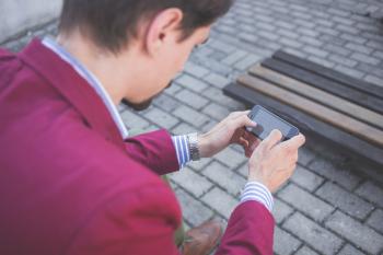 Man in Magenta Suit Jacket Holding Smartphone With Both Hands
