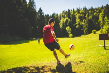 Man in Red T Shirt Playing Soccer during Daytime