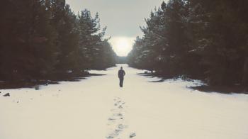 Man alone walking alone to the sun on snow in beautiful winter ...