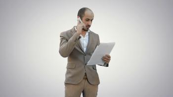 Young man in suit talking on the phone and holding papers on white ...