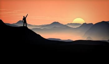 Man Raising Arm at the Top of the Mountain