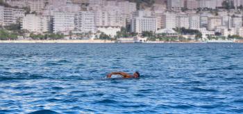 Man Swimming in a Body of Water White Concrete High Rise Building in Background