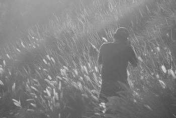 Man Taking Photo on Grass Field in Greyscale Photography