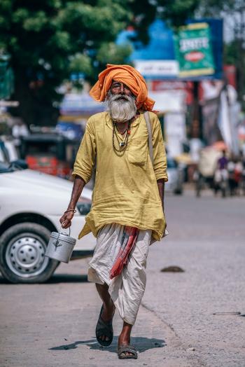 Man Walking on Street Carrying Metal Bucket