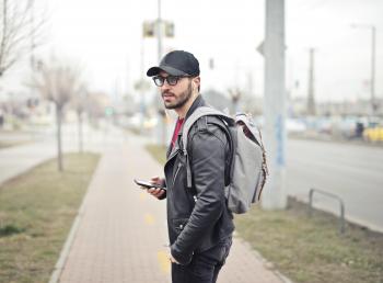 Man Wearing Black Leather Jacket Holding Smartphone