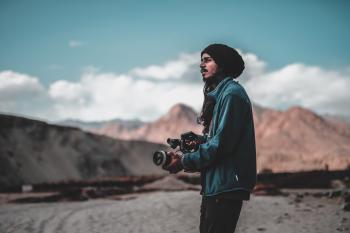 Man Wearing Jacket Holding Dslr Camera on Desert
