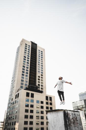Man Wearing White Long Sleeve Shirt Beside White and Black High Rise Building