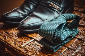 Man's Black Leather Shoes Near to Green and White Spotted Tie