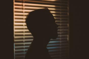 Man's Silhouette Near White Window Blinds