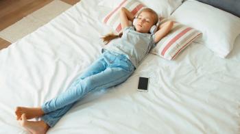 Girl child listening music headphones and lying on the bed. Zooming ...