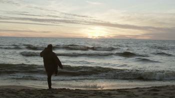 Young man throws sand and runs on the shore of the sea. Sad male at ...