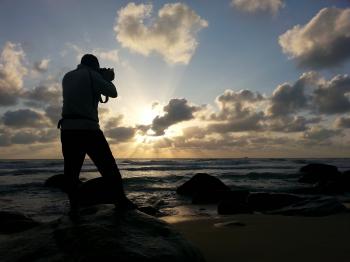 Person Capturing Photo Near Sea Under Clear Blue and White Cloudy Sky during Daytime