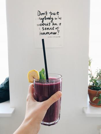 Person Holding Clear Drinking Glass With Purple Smoothie With Quotation Decor