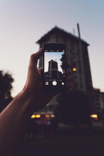 Person Holding Iphone Taking a Photo of Building
