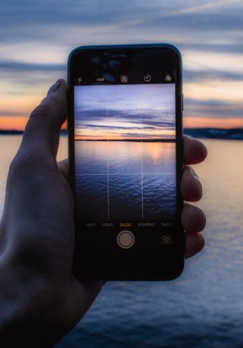 Person Holding Post-2014 Iphone Taking a Photo of Body of Water