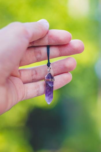 Person Holding Purple Gemstone Pendant
