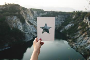 Person Holding Star Cutout Paper Facing Mountain