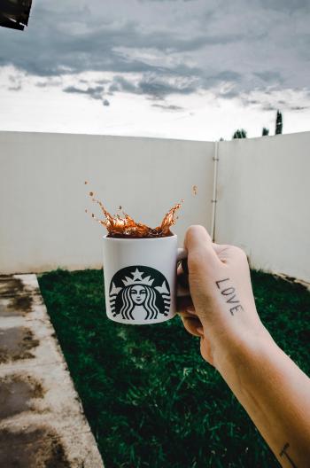 Person Holding Starbucks Cup With Brown Beverage