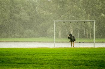 Person In Black Hoodie Riding Swing While Raining